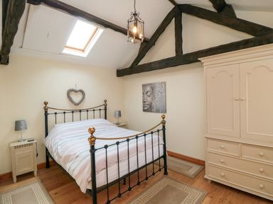 A bedroom with a metal bed frame bedside tables with lamps a wardrobe and a ceiling skylight at Barn Cottage High Normanby near Robin Hoods Bay