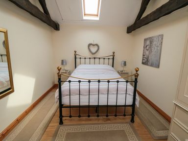 A bedroom with a metal bed frame a skylight and bedside tables with lamps at Barn Cottage in High Normanby near Robin Hood's Bay
