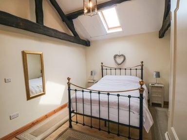 A bedroom with a metal bed frame a heart-shaped wall decoration and skylight window at Barn Cottage in High Normanby near Robin Hood's Bay