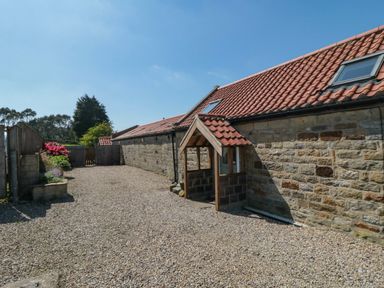 A stone exterior building with a red tiled roof and gravel driveway at Barn Cottage in High Normanby near Robin Hood's Bay