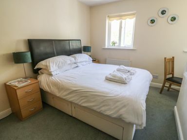 A bedroom with a double bed bedside tables lamps a wooden chair and a window at Bramble Cottage in Sedbergh