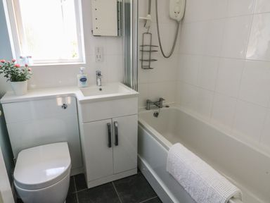 A bathroom with a toilet sink cabinet bathtub and shower at Bramble Cottage in Sedbergh