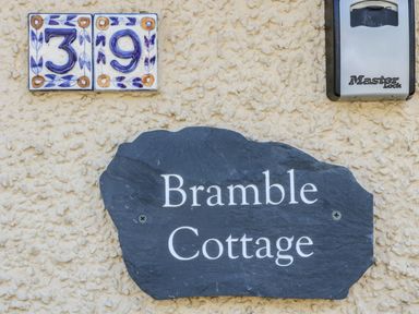 House number 39 in decorative tiles a black slate sign with Bramble Cottage and a silver Master Lock key safe on a textured wall at Bramble Cottage in Sedbergh
