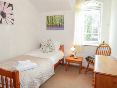 A small bedroom with a single bed side table wooden chair and chest of drawers at No 1 Railway Cottages Betws-y-Coed
