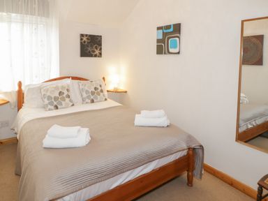 A bedroom with a double bed and folded towels on it at No 1 Railway Cottages in Betws-y-Coed