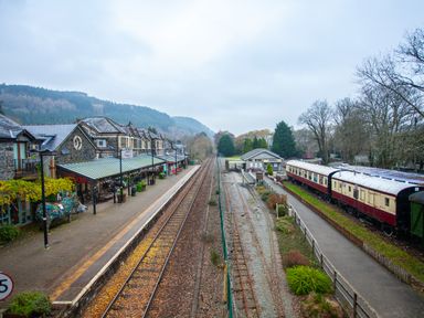 A train station with railway tracks a platform buildings and train carriages at No 1 Railway Cottages in Betws-y-Coed
