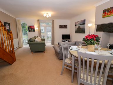 A living room with sofas dining table and chairs near stairs at No 1 Railway Cottages in Betws-y-Coed