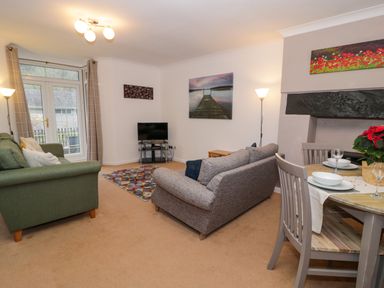 A living room with sofas and a television near a dining table at No 1 Railway Cottages in Betws-y-Coed