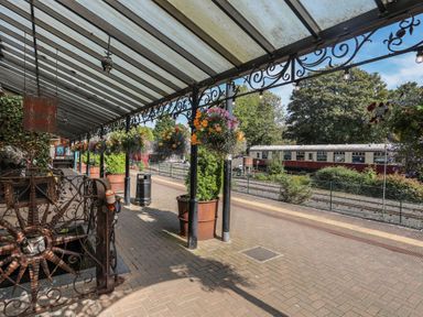 A train platform with hanging flower baskets and a vintage train carriage at No 1 Railway Cottages in Betws-y-Coed