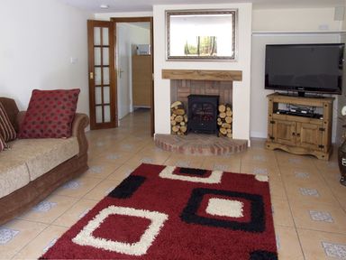 A living room with a sofa cushions fireplace and television on a wooden stand at Rosewaters Cottage Astley Burf near Stourport-on-Severn