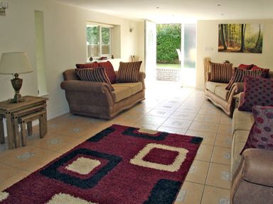 A living room with two brown sofas and a patterned rug at Rosewaters Cottage in Astley Burf near Stourport-on-Severn