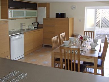 A kitchen and dining area with wooden cabinets and a table set for six at Rosewaters Cottage in Astley Burf near Stourport-on-Severn