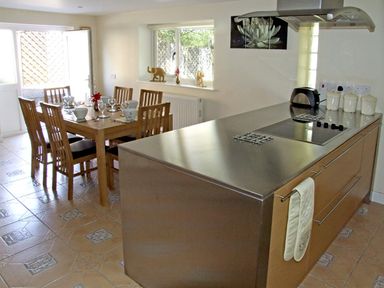 A kitchen with a stainless steel countertop and a wooden dining table with chairs at Rosewaters Cottage in Astley Burf near Stourport-on-Severn