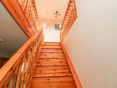 A wooden staircase with railings and a painting on the wall at Fern View House in Beaufort near Killorglin County Kerry