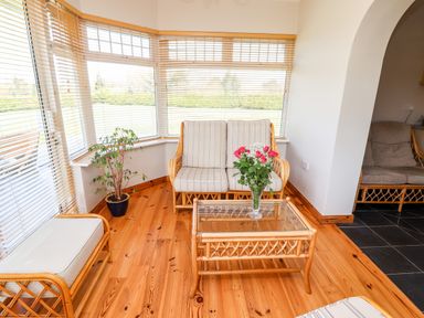 A sitting area with rattan furniture and flowers on a glass table at Fern View House in Beaufort near Killorglin County Kerry