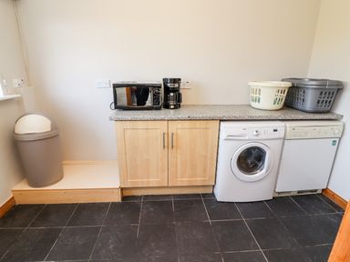 A utility room with a washing machine dishwasher microwave coffee maker and laundry baskets at Fern View House in Beaufort near Killorglin County Kerry