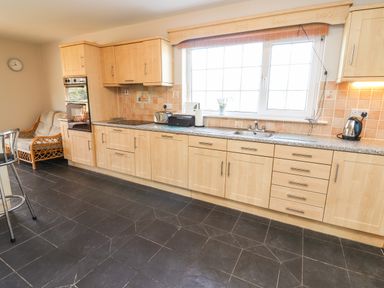 A kitchen with light wood cabinets a large window and black tiled floor at Fern View House Beaufort near Killorglin County Kerry