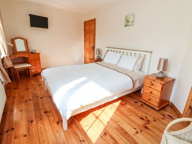 A bedroom with a bed a dressing table and wooden furniture at Fern View House in Beaufort near Killorglin County Kerry