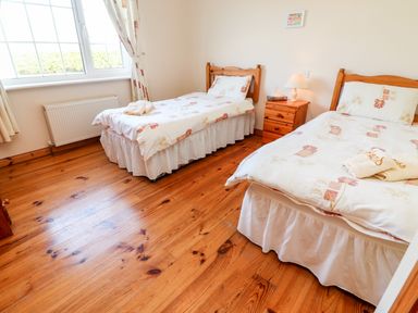 A bedroom with two single beds a wooden nightstand and a window at Fern View House in Beaufort near Killorglin County Kerry