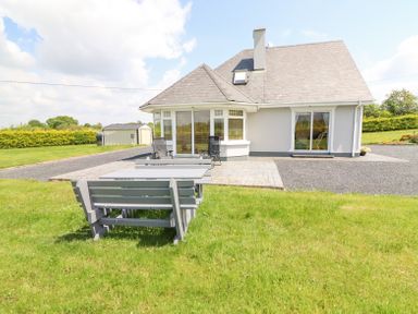 A house with a gray roof white walls lawn and outdoor picnic tables at Fern View House in Beaufort near Killorglin County Kerry