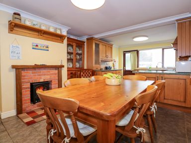 A kitchen and dining area with wooden cabinets and table at Brynteg in Llwyngwril