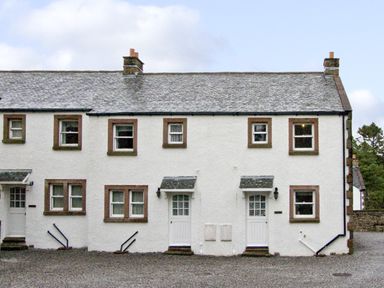 The exterior of a white two-story building with multiple windows and two white doors at William Court Cottage in Irton Hall near Wastwater