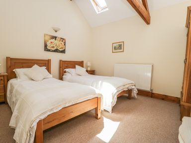 A bedroom with two single wooden beds a nightstand and a wardrobe at Wheelhouse Cottage in Sowerby outskirts of Thirsk