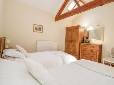 A bedroom with two single beds wooden wardrobe and chest of drawers at Wheelhouse Cottage in Sowerby outskirts of Thirsk