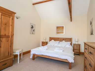 A bedroom with a wooden bed and bedside tables a wardrobe a chest of drawers and framed pictures on walls at Wheelhouse Cottage in Sowerby outskirts of Thirsk