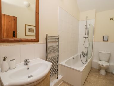 A bathroom with a sink mirror towel rack bathtub and toilet at Wheelhouse Cottage in Sowerby outskirts of Thirsk