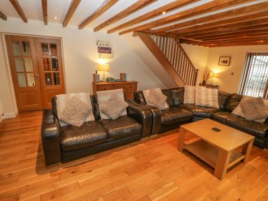 A living room with brown leather sofas cushions wooden coffee table wooden beams on ceiling at Cefn-Yr-Efail in Golan near Porthmadog