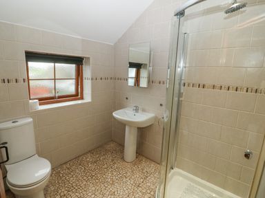 A bathroom with a toilet sink mirror shower and a window at Cefn-Yr-Efail in Golan near Porthmadog