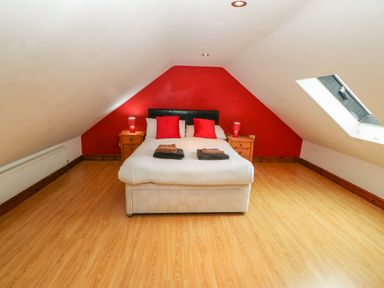 A bedroom with a double bed red pillows two bedside tables and a skylight window at Cefn-Yr-Efail in Golan near Porthmadog