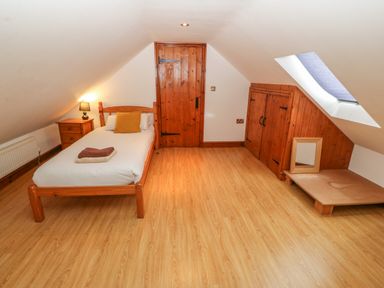 A bedroom with a single bed bedside table with lamp wooden door built in wooden cupboards and skylight window at Cefn-Yr-Efail in Golan near Porthmadog