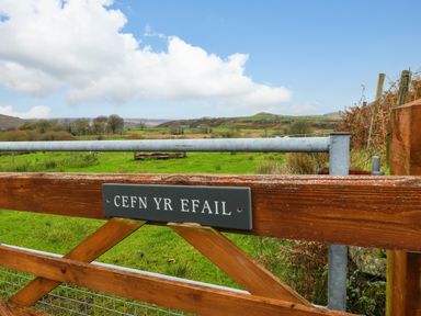 A wooden gate with a sign that reads Cefn Yr Efail with fields and hills in the background at Cefn-Yr-Efail Golan near Porthmadog
