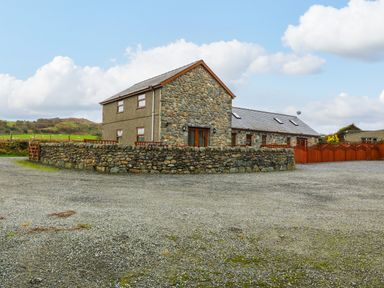 A stone house with a gravel driveway and a stone wall at Cefn-Yr-Efail in Golan near Porthmadog
