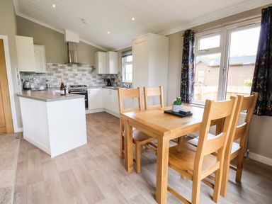 A kitchen and dining area with wooden table and chairs near a window at Callow Lodge 15 Beaconsfield Farm Holiday Park near Shrewsbury