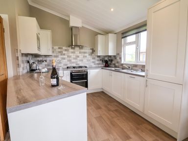 A kitchen with white cabinets wooden countertops a stove and window at Callow Lodge 15 Beaconsfield Farm Holiday Park near Shrewsbury