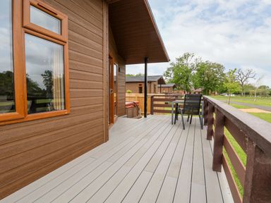 A wooden deck with table and chair at Callow Lodge 15 Beaconsfield Farm Holiday Park near Shrewsbury