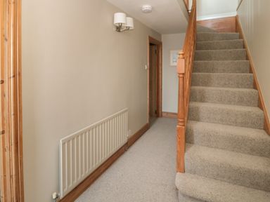 A hallway with carpeted stairs and a radiator at Jackson Cottage in Alnmouth