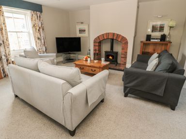 A living room with sofas a wooden coffee table a fireplace and a television at Jackson Cottage in Alnmouth