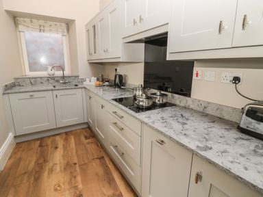 A kitchen with white cabinets and grey marble countertops at Jackson Cottage in Alnmouth