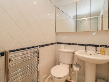 A bathroom with a toilet sink mirror and towel rack at Jackson Cottage in Alnmouth