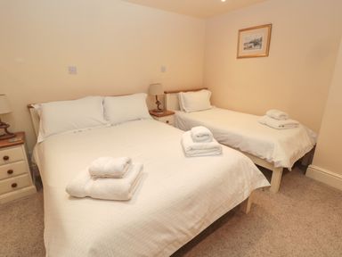 A bedroom with a double bed and a single bed each with white linens and folded towels on top at Jackson Cottage in Alnmouth