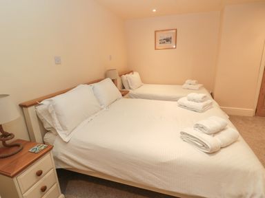 A bedroom with two beds a bedside table with a lamp and towels on the beds at Jackson Cottage in Alnmouth