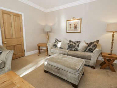 A living room with a sofa and ottoman at Tyddyn Goronwy in Talybont