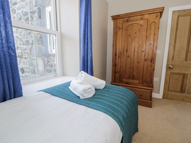 A bedroom with a bed and a wardrobe at Tyddyn Goronwy in Talybont