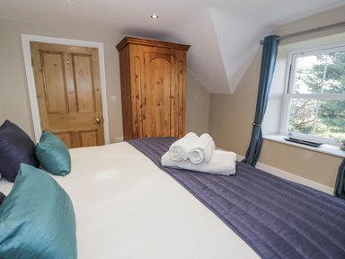 A bedroom with a bed and wardrobe at Tyddyn Goronwy in Talybont