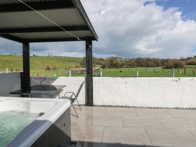 An outdoor area with a hot tub and seating at Meadow View in Laugharne