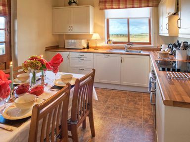 A kitchen with wooden countertops a dining table set with dishes candles and flowers at Barmoor Ridge in Lowick near Holy Island